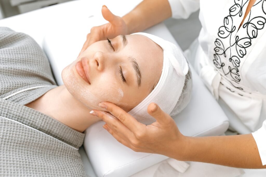Facial skin care procedures in a beauty salon. The cosmetologist applies a special cream, scrub