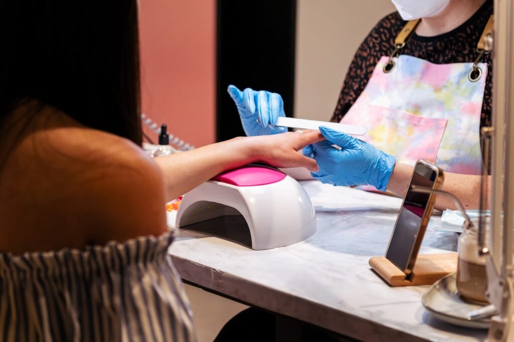 hands of a beautician filing nails during manicure