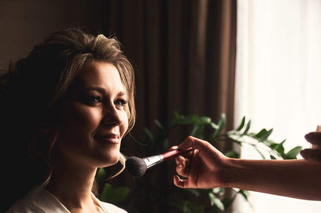 Make-up artist with brush make wedding makeup for lovely lady bride