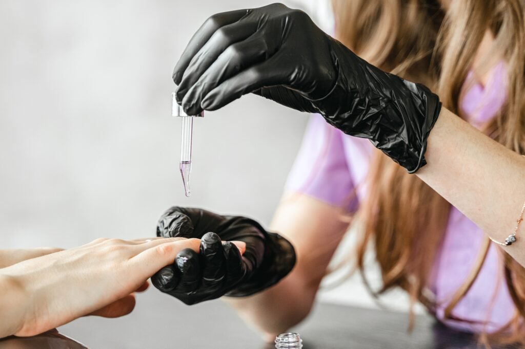 Professional master manicurist at beauty salon. Manicure cuticle oil service, hands treatments,
